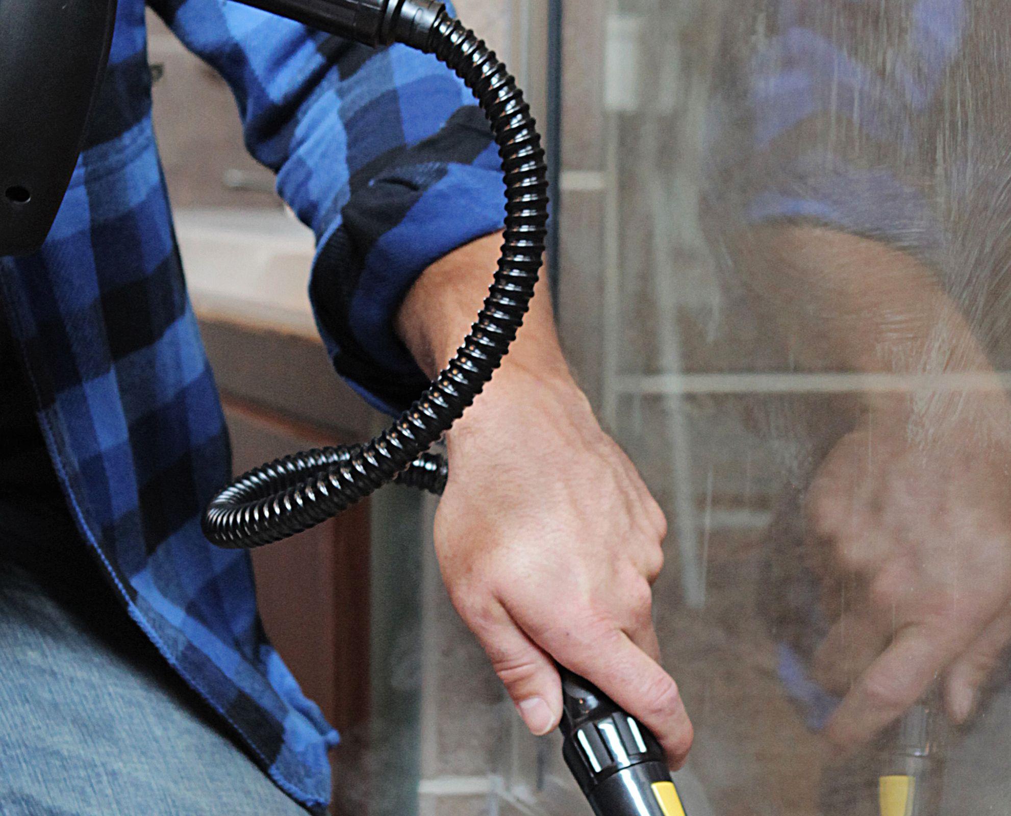Image of the PP350 steam cleaner being used on a dirty window showcasing the hose attachment as well as use for multiple surfaces.