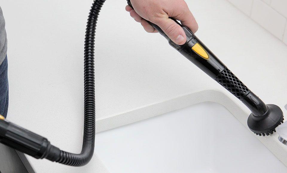 A person using a Poulan Pro PP230 Handheld Steam Cleaner extension nozzle to clean a sink